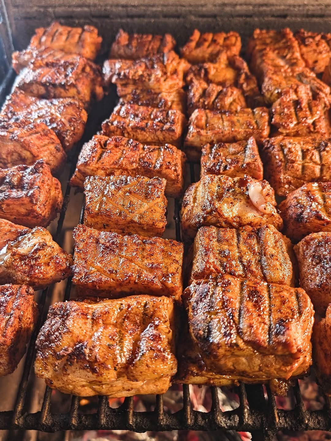 Rows of smoked pork belly over the coals