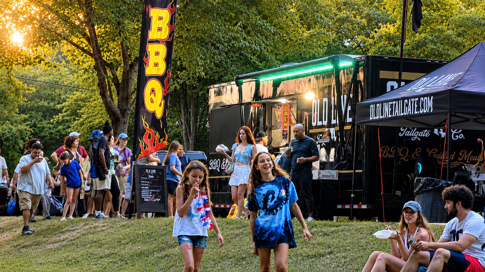 The Old Line truck at a summer festival, window open, crowd on the grass