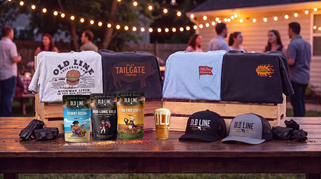The Old Line Tailgate co. lineup: tees, trucker hats, Old Line Provisions rubs, charcoal, and a pint glass at a backyard cookout