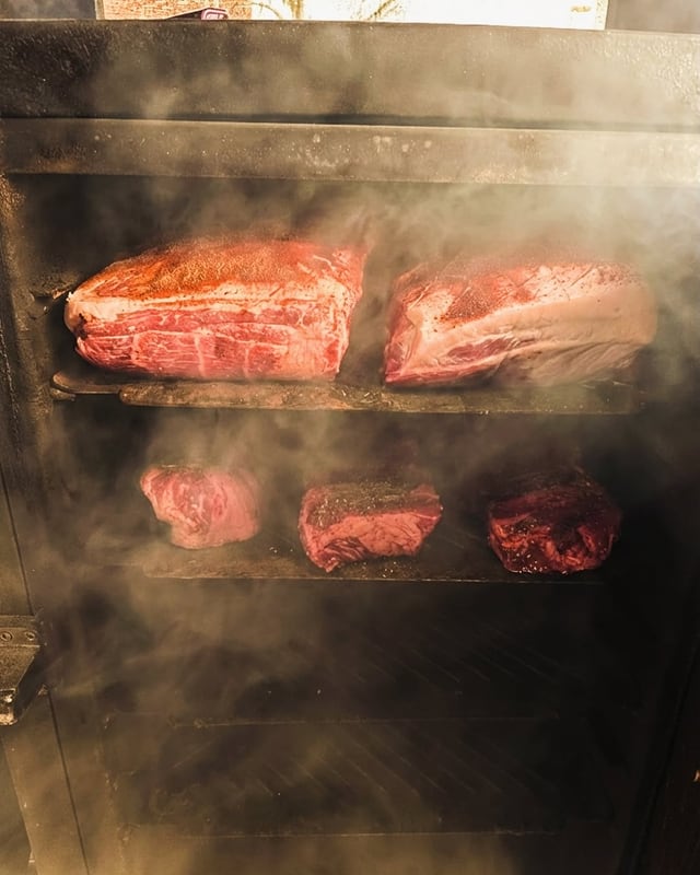 Meat on the smoker racks in the smoke