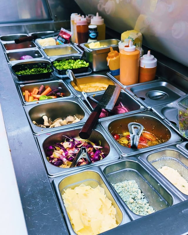 The prep line: pans of chopped onion, peppers, sauces and slaw