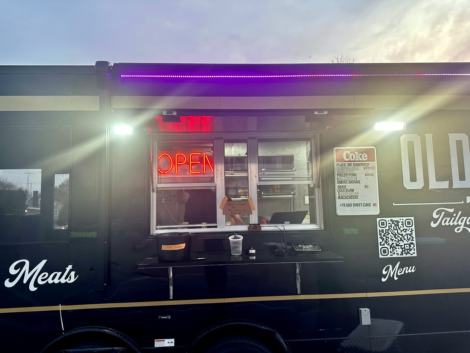 The Old Line truck's service window at dusk – OPEN sign lit, menu board and counter ready